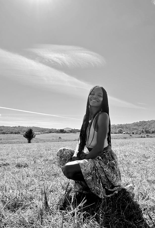 Jeanette Lynn kneeling and smiling in a sunlit field